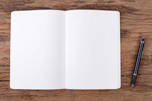 Blank note pad with pen on wood background photo