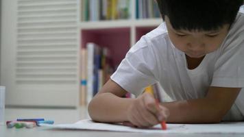 un niño asiático de ocho años está haciendo su tarea de colorear en casa video