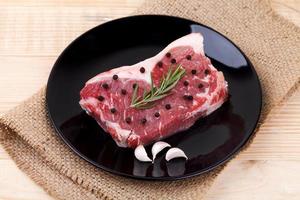 Raw red sirloin steak with rosemary, garlic , pepper on wood table photo