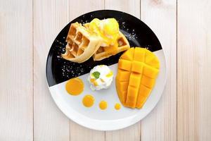 Top view waffle with ice cream and mango on wood table photo