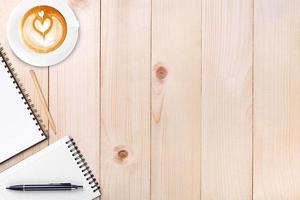 An open blank notebook with pencil and a cup of coffee on wooden table. Latte art coffee on top photo