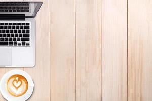 Top view cup of latte art coffee and laptop computer notebook on wooden table photo