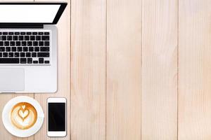 Top view laptop computer or notebook,mobile phone and cup of latte art coffee on wooden table.Business template mock up for adding your text. photo