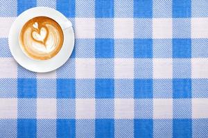 Top view latte art coffee on fabric textile texture background photo