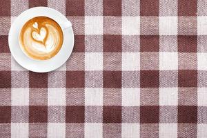 Top view latte art coffee on fabric textile texture background photo