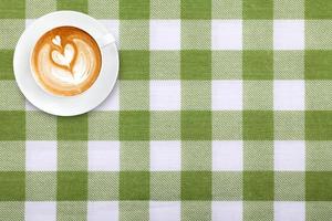 Top view latte art coffee on fabric textile texture background photo