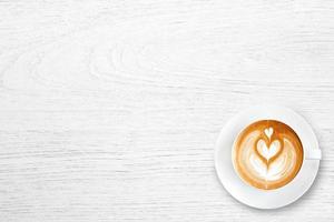 Cup of latte coffee with heart on white  wooden table photo