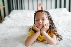 Little girl lying on bed and look at camera. photo