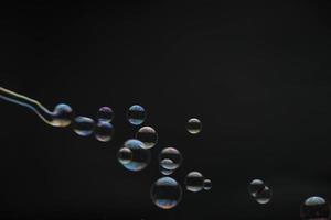 burbujas de jabón voladoras sobre fondo negro. pompas de jabón abstractas con reflejos coloridos. pompas de jabón en movimiento de fondo.