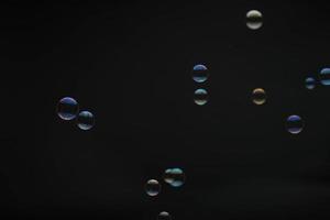 Flying soap bubbles on black background. Abstract soap bubbles with colorful reflections. Soap bubbles in motion background. photo