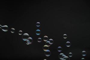 burbujas de jabón voladoras sobre fondo negro. pompas de jabón abstractas con reflejos coloridos. pompas de jabón en movimiento de fondo.