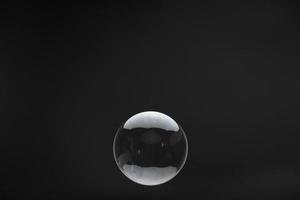 Flying soap bubbles on black background. Abstract soap bubbles with reflections. Soap bubbles in motion background. photo