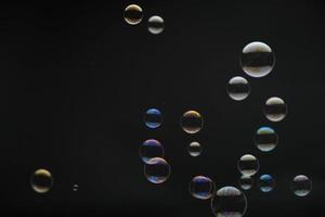 Flying soap bubbles on black background. Abstract soap bubbles with colorful reflections. Soap bubbles in motion background. photo