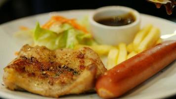 Closeup of people dropping sauce to chicken steak with sausage french fries and salad dish video