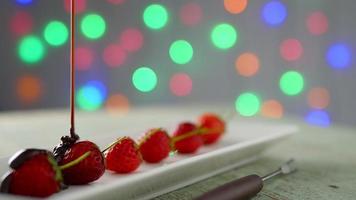 Liquid chocolate poring to strawberry over colorful light bokeh background