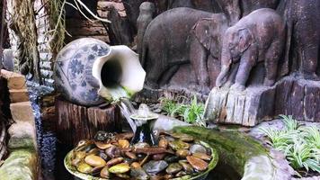 Outdoor decoration pond corner in relax area with small waterfall and fountain with concrete sculptures elephant background video