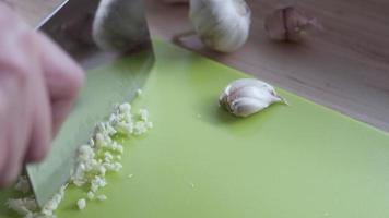 Lady prepare fresh chopped garlic using hand knife in the kitchen - close up food preparing concept