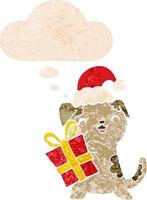 cute cartoon puppy with christmas present and hat and thought bubble in retro textured style vector