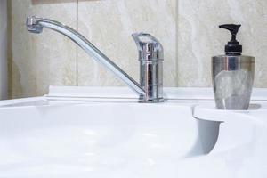 water tap sink with faucet in expensive loft bathroom. detail of a corner shower cabin with wall mount shower attachment photo