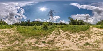 vista de ángulo de 360 grados de panorama hdri esférico completo sin fisuras cerca de torres de pilón eléctrico de alto voltaje en camino de grava en bosque en proyección equirectangular, contenido vr ar foto