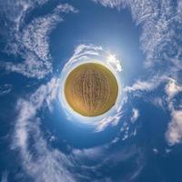 Little planet transformation of spherical panorama 360 degrees. Spherical abstract aerial view in field with awesome beautiful clouds. Curvature of space. photo