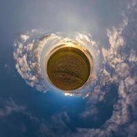Little planet transformation of spherical panorama 360 degrees. Spherical abstract aerial view in field with awesome beautiful clouds. Curvature of space. photo