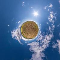 Little planet transformation of spherical panorama 360 degrees. Spherical abstract aerial view in field with awesome beautiful clouds. Curvature of space. photo