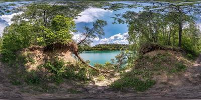 vista de ángulo de 360 grados de panorama hdri esférico completo en bosque de pinares con raíces de árboles torpes en la costa de un enorme lago verde en proyección equirectangular, contenido de realidad virtual listo vr ar foto