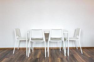 sillas blancas de madera con una mesa en el fondo de una pared blanca en el interior foto