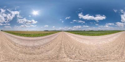 Full spherical seamless hdri panorama 360 degrees angle view on no traffic white sand gravel road among fields with clear sky with beautiful clouds in equirectangular projection, VR AR content photo