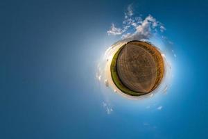 Little planet transformation of spherical panorama 360 degrees. Spherical abstract aerial view in field with awesome beautiful clouds. Curvature of space. photo