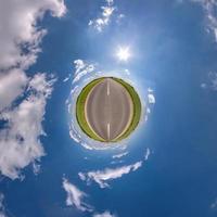 tiny planet in blue sky with sun and beautiful clouds. Transformation of spherical panorama 360 degrees. Spherical abstract aerial view. Curvature of space. photo