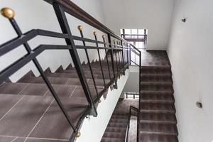 A white stairs  emergency and evacuation exit stair in up ladder in a new office building with sunshine throught window photo