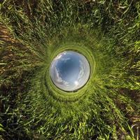 Inversion of little planet transformation of spherical panorama 360 degrees. Spherical abstract aerial view in field with awesome beautiful clouds. Curvature of space. photo