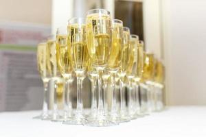 lot of blurred glasses with champagne on the reception party table on light background photo