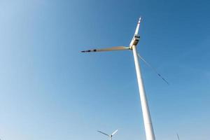 rotating blades of a windmill propeller on blue sky background. Wind power generation. Pure green energy. photo