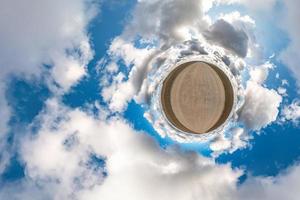 Little planet transformation of spherical panorama 360 degrees. Spherical abstract aerial view in field with awesome beautiful clouds. Curvature of space. photo