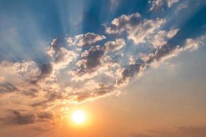 Blue sky background with evening fluffy curly rolling altocumulus altostratus clouds with setting sun. Good windy weather photo