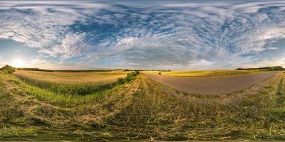 panorama esférico de hdri vista angular de 360 grados cerca de la carretera asfaltada entre los campos en la puesta de sol de la tarde de verano con nubes cirrocúmulos en proyección equirectangular, contenido de realidad virtual listo vr ar foto