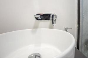 water tap sink with faucet in expensive loft bathroom. detail of a corner shower cabin with wall mount shower attachment photo