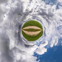 tiny planet in blue sky with sun and beautiful clouds. Transformation of spherical panorama 360 degrees. Spherical abstract aerial view. Curvature of space. photo