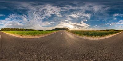 panorama esférico de hdri vista angular de 360 grados en carretera asfaltada entre campos en la puesta de sol de la tarde de verano con nubes impresionantes en proyección equirectangular, contenido de realidad virtual listo vr ar foto