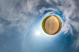 Little planet transformation of spherical panorama 360 degrees. Spherical abstract aerial view in field with awesome beautiful clouds. Curvature of space. photo