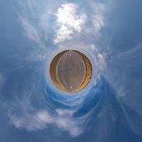 tiny planet in blue sky with sun and beautiful clouds. Transformation of spherical panorama 360 degrees. Spherical abstract aerial view. Curvature of space. photo