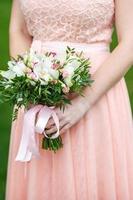 The bride in pink dress in nature with wedding  beautiful bouquet of light several color roses flowers.  Walk the newlyweds. Wedding day. The best day of a young couple photo