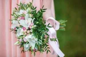 The bride in pink dress in nature with wedding  beautiful bouquet of light several color roses flowers.  Walk the newlyweds. Wedding day. The best day of a young couple photo