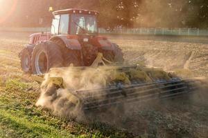 el cultivador del tractor ara la tierra, se prepara para los cultivos. polvo en el campo foto