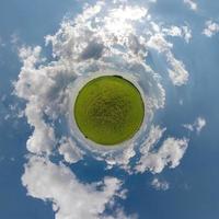 tiny planet in blue sky with beautiful clouds with transformation of spherical panorama 360 degrees. Spherical abstract aerial view. Curvature of space. photo