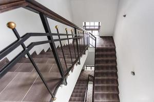 una escalera blanca de emergencia y salida de evacuación en la escalera de un nuevo edificio de oficinas con sol a través de la ventana foto