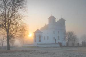 hermosa iglesia católica a principios de la mañana de niebla de otoño foto